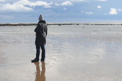 Rear view of man on beach against sky