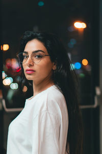 Portrait of young woman standing in city at night