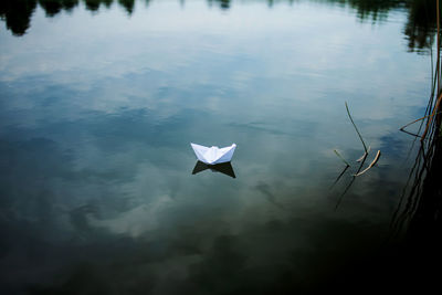 White paper boat sailing on blue water surface of lake.