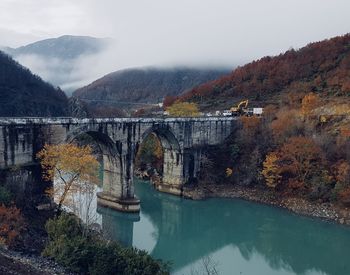 Bridge over river by mountains against sky