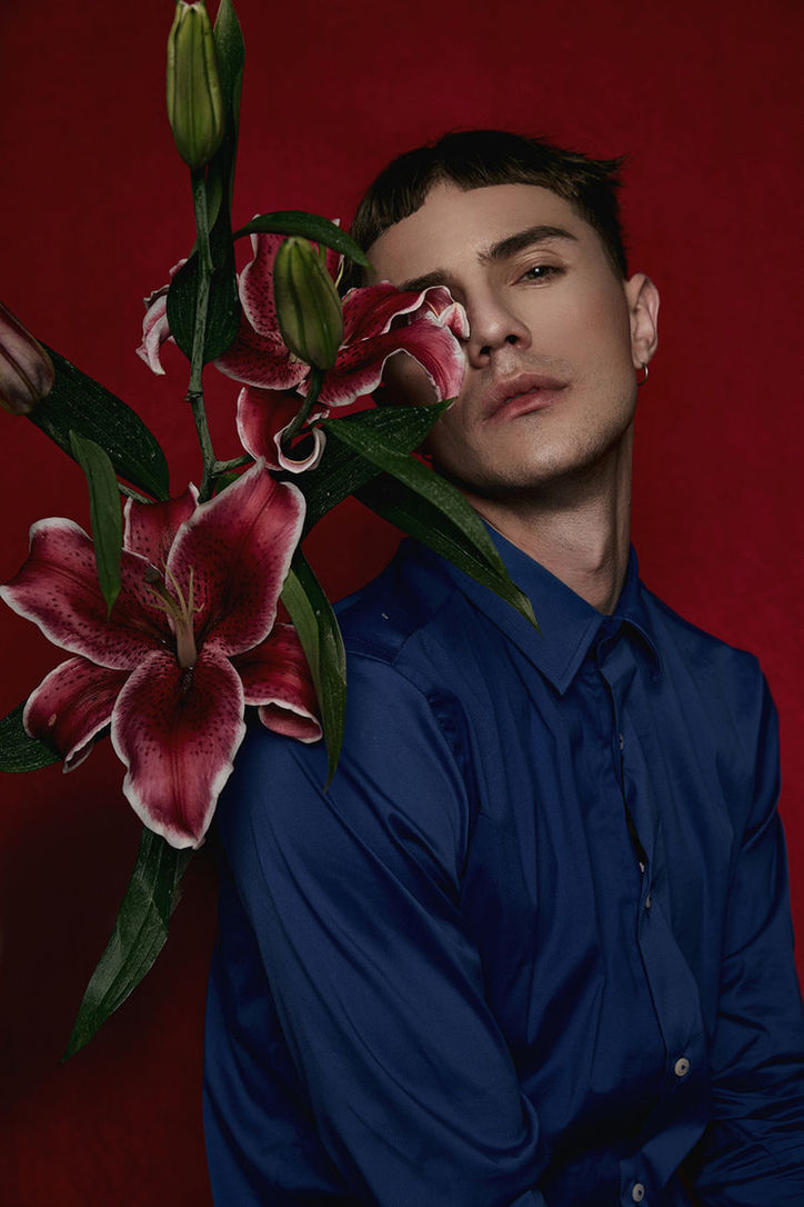 CLOSE-UP OF YOUNG MAN AGAINST RED AND YELLOW ROSES