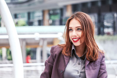 Close-up of smiling young businesswoman standing on elevated walkway 