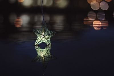 Reflection of illuminated star shape decoration on lake at night