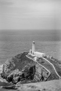 Lighthouse by sea against sky