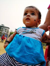 Cute baby girl sitting in park against clear sky