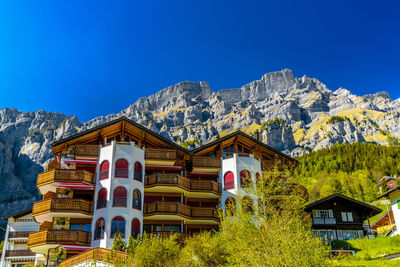 Low angle view of house and trees against clear blue sky