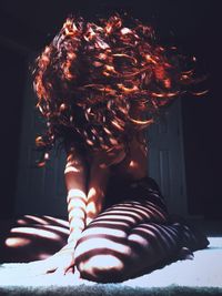 Woman tossing hair while sitting on bed at home