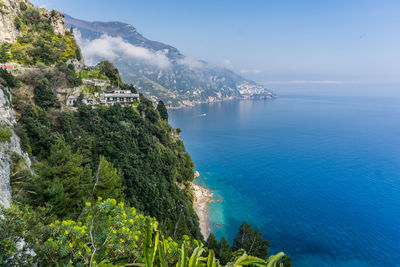 Scenic view of sea by mountains against blue sky