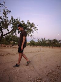 Side view of boy standing on land against sky