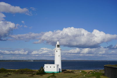 Lighthouse by sea against sky