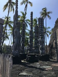 Statue by palm trees against sky