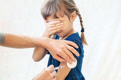 Hands giving vaccination to girl