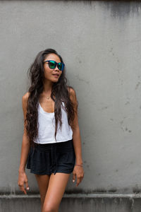 Portrait of a smiling young woman standing against wall