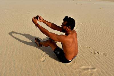 High angle view of shirtless man on sand at beach