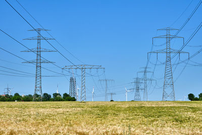 Electricity pylons and power lines with wind turbines in the back in germany