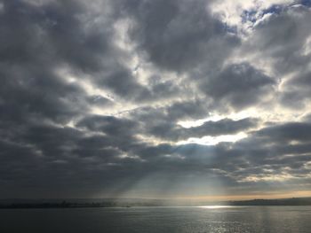 Sunlight streaming through clouds over sea