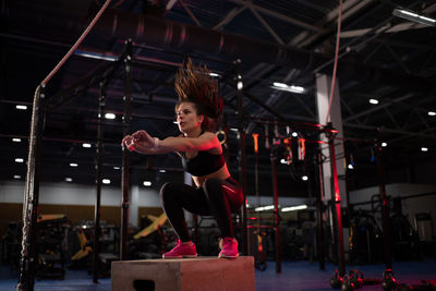 Powerful sportswoman jumping on gym box