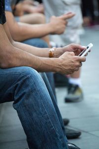 Low angle view of man using mobile phone while sitting by street