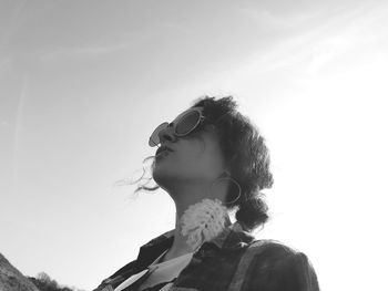 Portrait of young woman looking away against sky