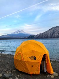 Yellow tent on beach by sea against sky