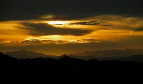 Scenic view of silhouette mountains against romantic sky at sunset