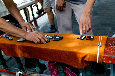 Midsection of men playing dominos on table