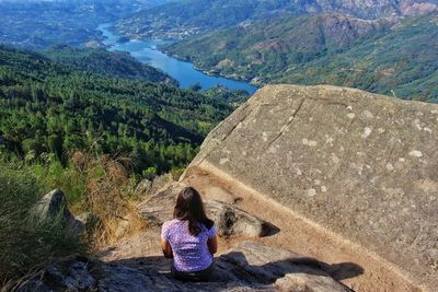 Rear view of woman sitting on mountain
