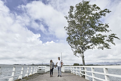 People standing by sea against sky