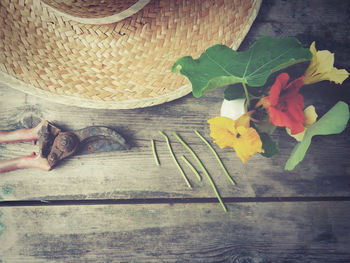 Directly above shot of wicker hat and pruning shears next to flower vase on table