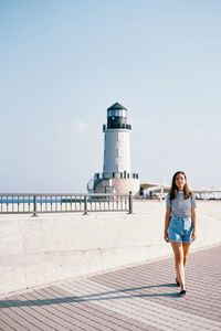 Rear view of woman standing by sea against sky