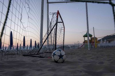 Soccer ball on beach against sky during sunset