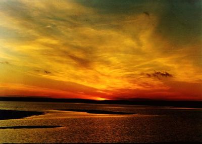 Scenic view of sea against dramatic sky during sunset