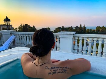 Rear view of woman in swimming pool against sky
