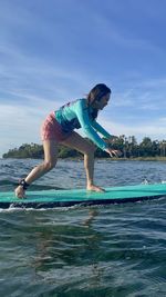 Rear view of woman jumping at beach against sky