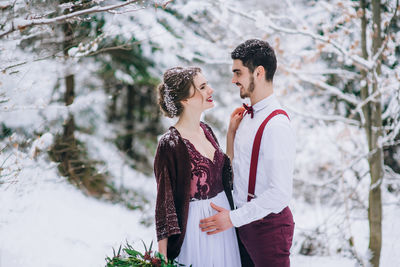 Friends standing on snow covered tree