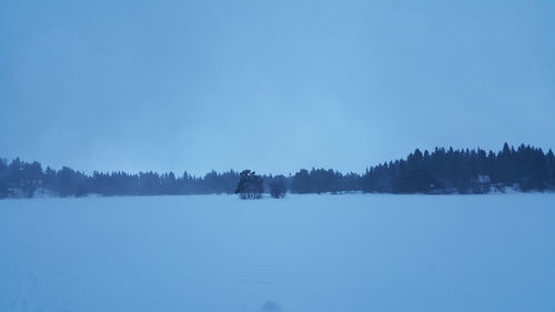 Snow covered landscape against clear blue sky