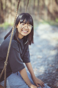 Portrait of smiling girl sitting on swing outdoors