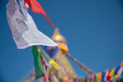 Low angle view of flags hanging against clear blue sky