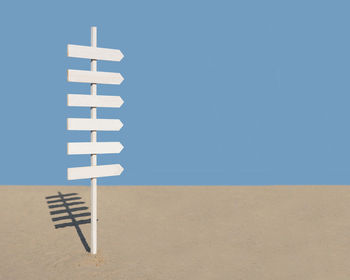 White umbrella on sand against blue sky