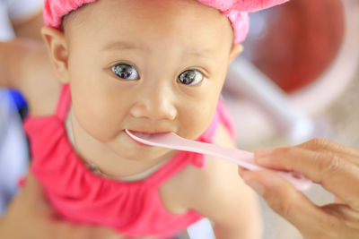 Cropped hand of woman feeding daughter with spoon at home