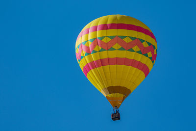 Low angle view of a hot air balloon floats in a clear blue sky on a sunny day
