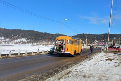 Cars on street by snowcapped mountain against sky