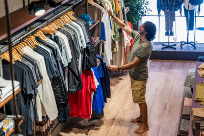 From above view man customer choosing t-shirts in a clothing store