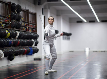 Woman in fencing outfit practicing at gym