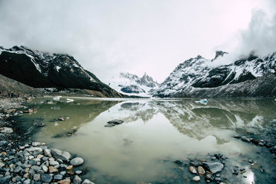 Glacial lake with snowcapped mountains in the background in winter