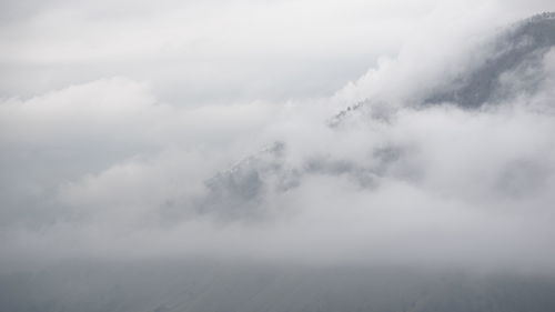 Scenic view of fog covered mountains against sky