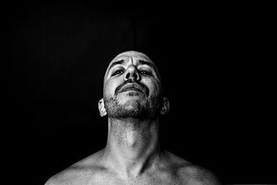 Portrait of shirtless man against black background