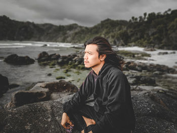 Young man sitting on rock at beach