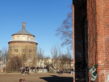 Group of people in front of building against clear blue sky