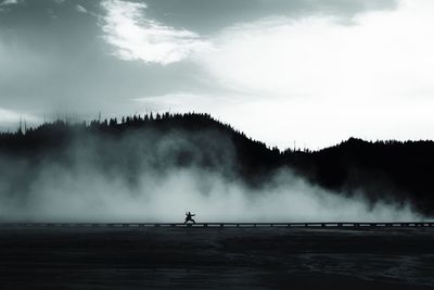 Silhouette girl doing karate by geyser at yellowstone national park against sky